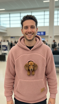 Man wearing a pink Kangapaw hoodie with a dachshund puppy peeking out of the chest window